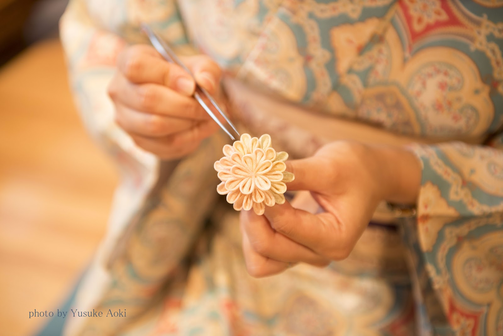 Hands using tweezers to fold a chrysanthemum flower in tsumami zaiku