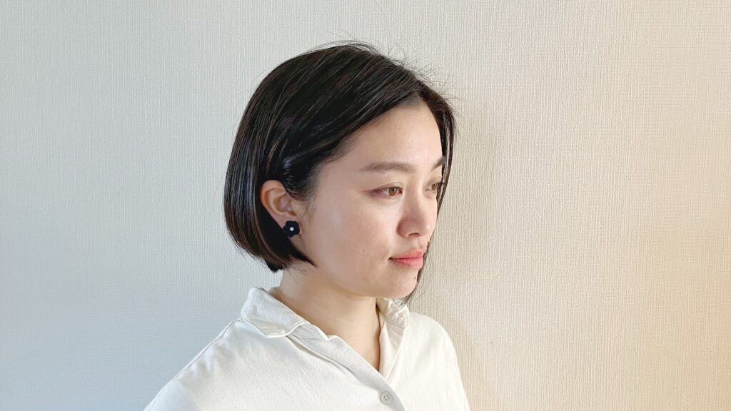 Woman wearing a navy tsumami zaiku flower stud earring with an everyday shirt