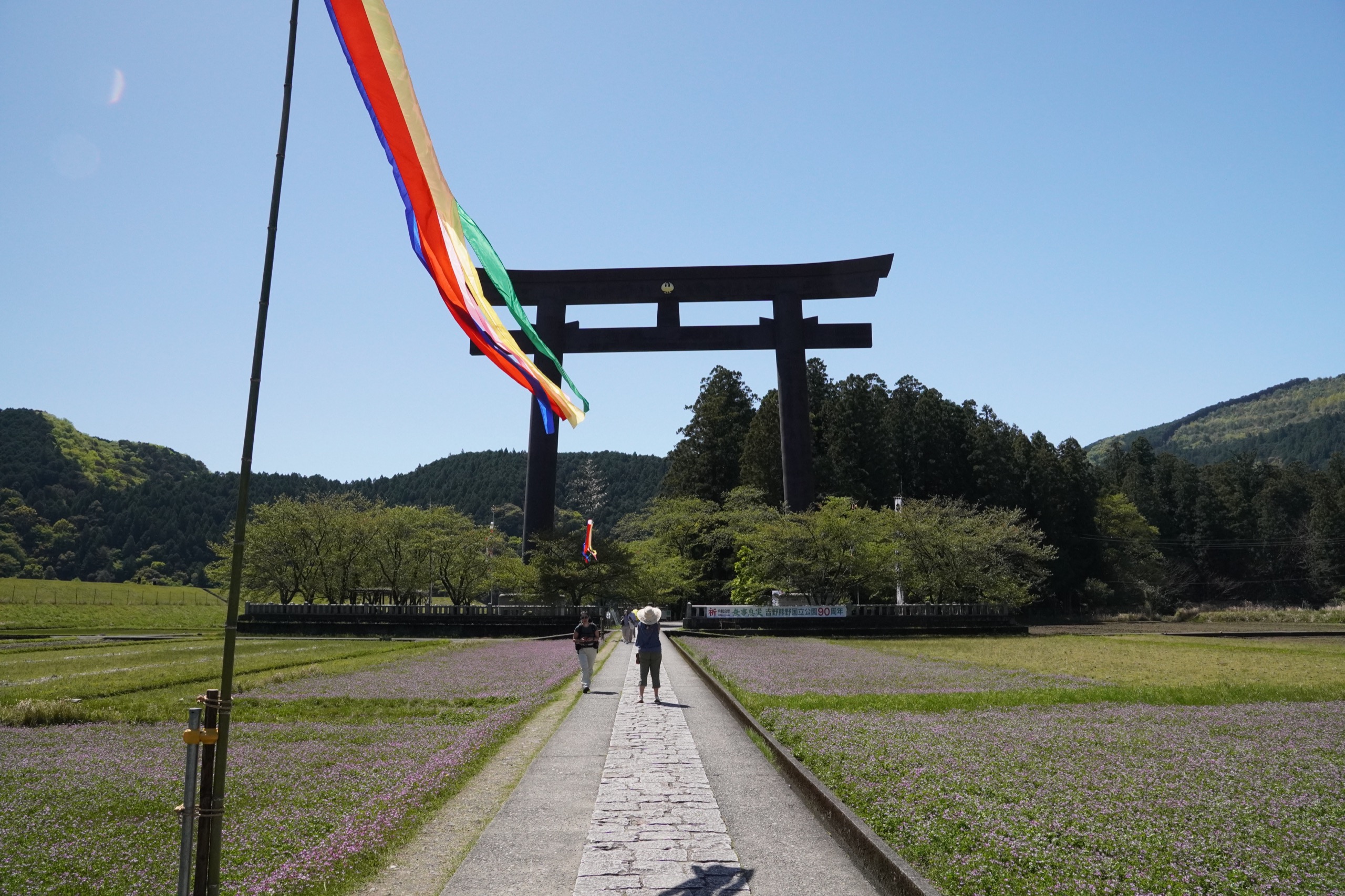 The Ōyunohara great torii of Kumano rising above rice paddies and pilgrims in the Kii Mountains
