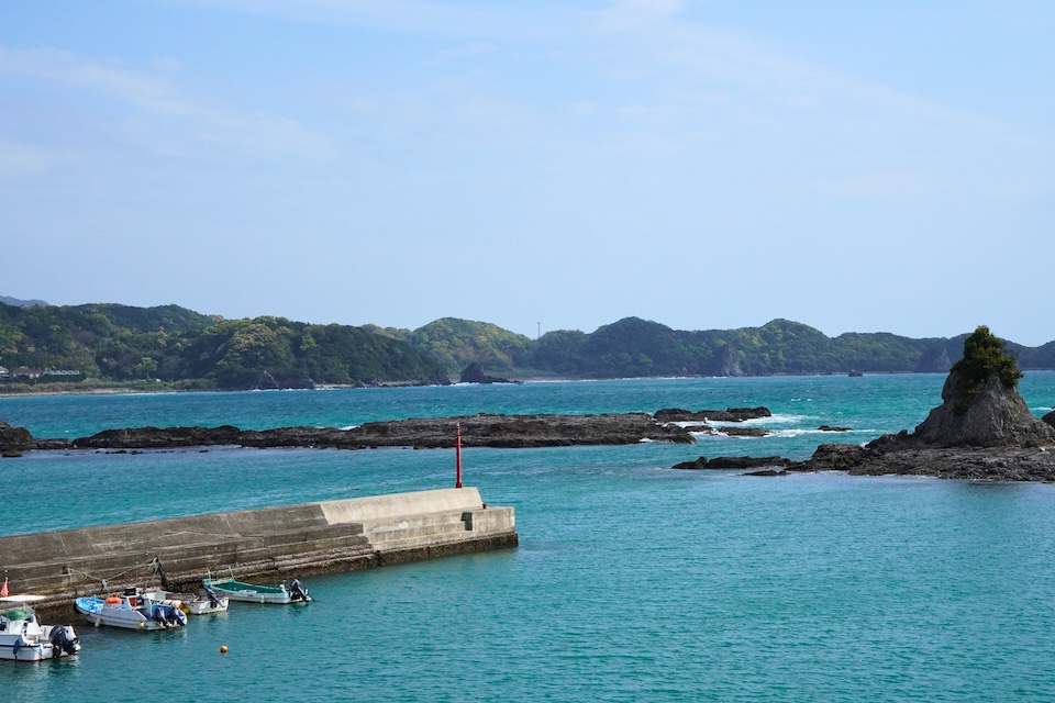 Fishing boats moored along a breakwater in the turquoise water of Katsuura Bay in Wakayama