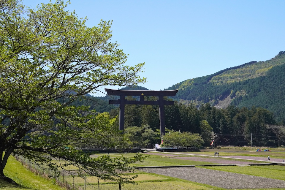 The great torii gate of Oyunohara rising above the trees, marking the original site of Kumano Hongu Taisha