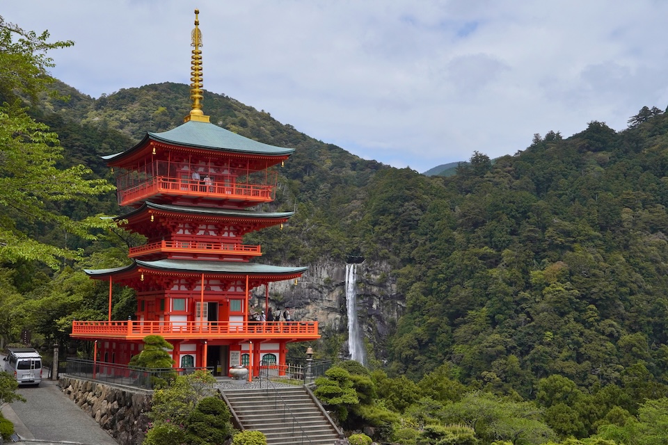 The vermilion three-storied pagoda of Seiganto-ji beside Kumano Nachi Taisha with Nachi Falls behind it