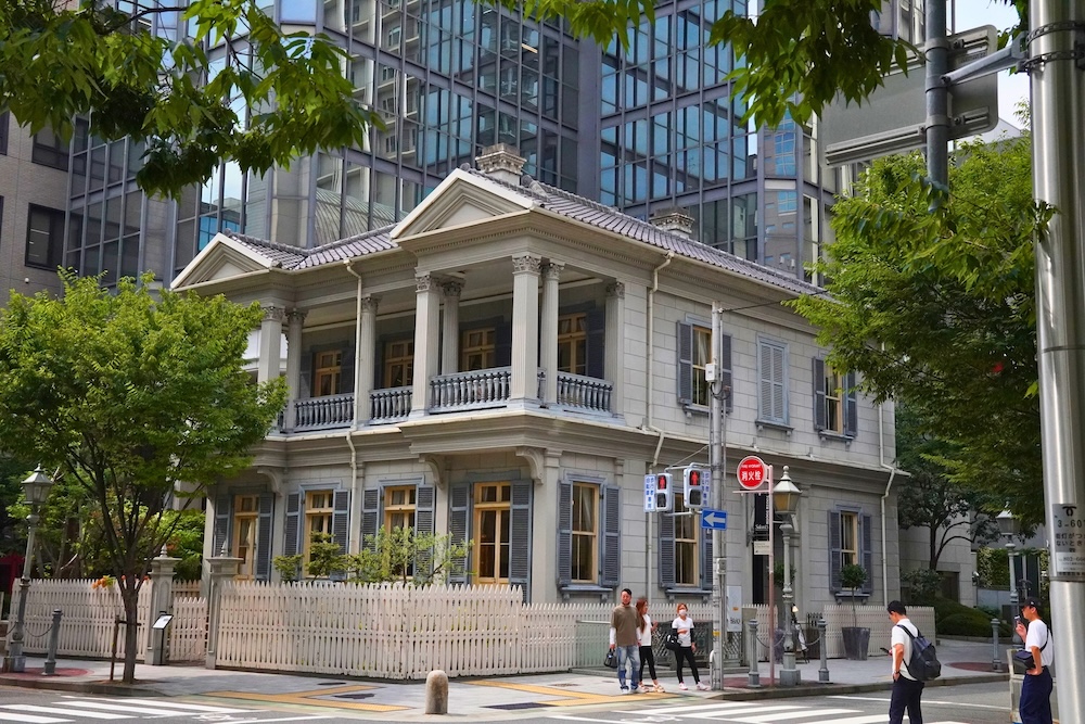 A white colonial-style building in front of modern towers in the Former Foreign Settlement, Kobe