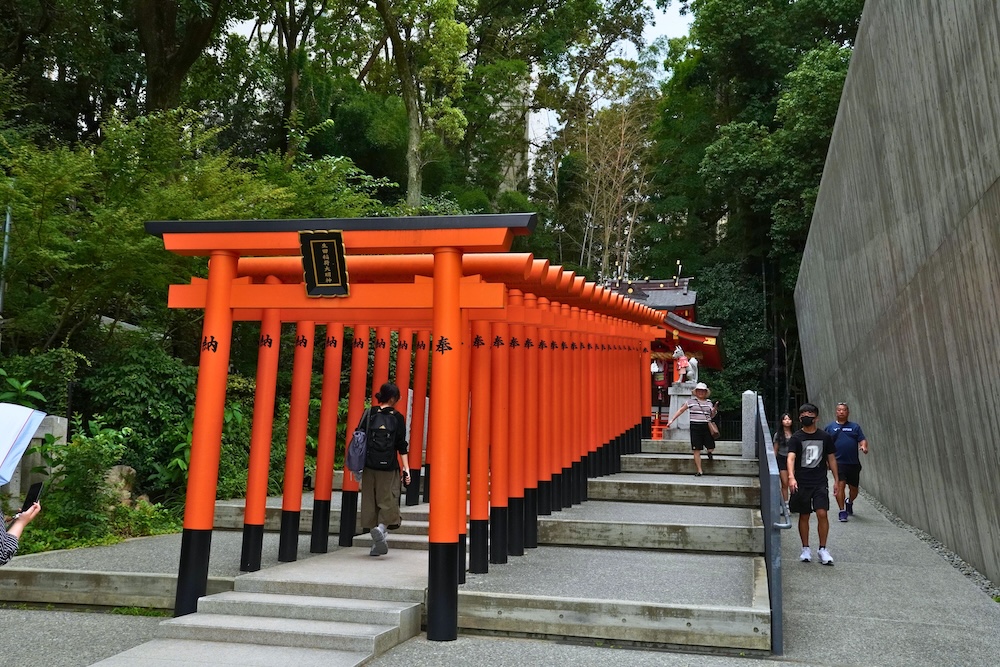 A row of red torii gates leading up stone steps at Ikuta Shrine in Kobe