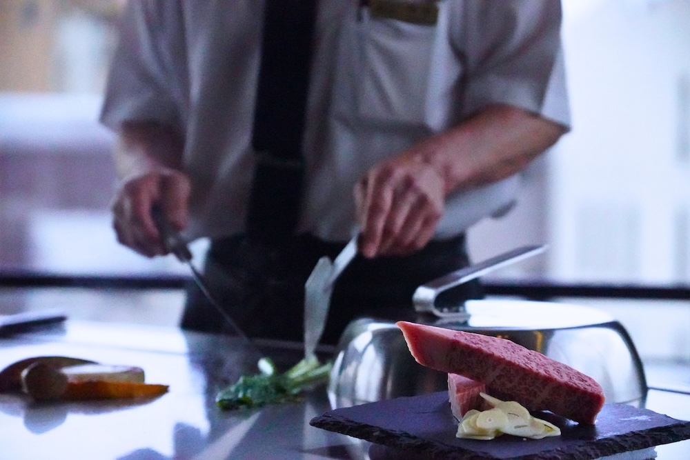 A chef preparing Kobe beef on the teppan at the counter of Misono in Kobe